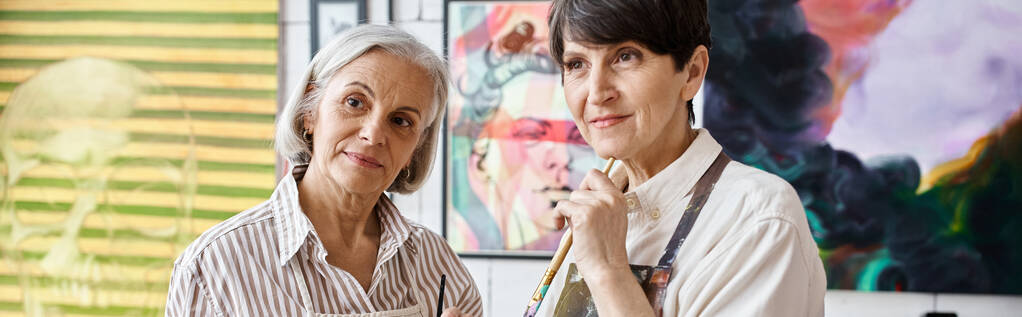 Két nő csodálkozva áll egy nagy festmény előtt egy művészeti stúdióban.. - Fotó, kép