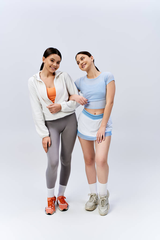 Dvě krásné a brunetky dospívající dívky ve sportovním oblečení, stojící vedle sebe, vyzařující sebevědomí a přátelství vibruje. - Fotografie, Obrázek