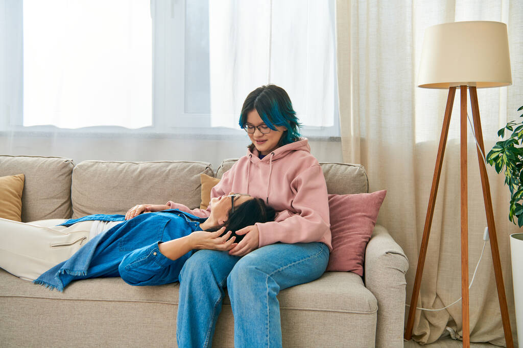 Eine asiatische Frau in Freizeitkleidung sitzt auf einer Couch und genießt einen friedlichen Moment miteinander. - Foto, Bild