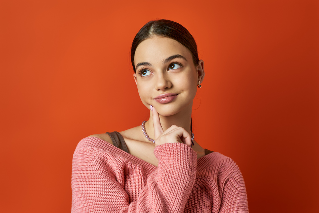 Egy barna tinédzser lány rózsaszín pulóverben pózol egy fotóhoz vibráló stúdióban.. - Fotó, kép
