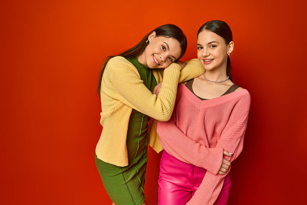 Twee mooie brunettes, tienervrienden, samen voor een levendige rode muur in een studio. - Foto, afbeelding