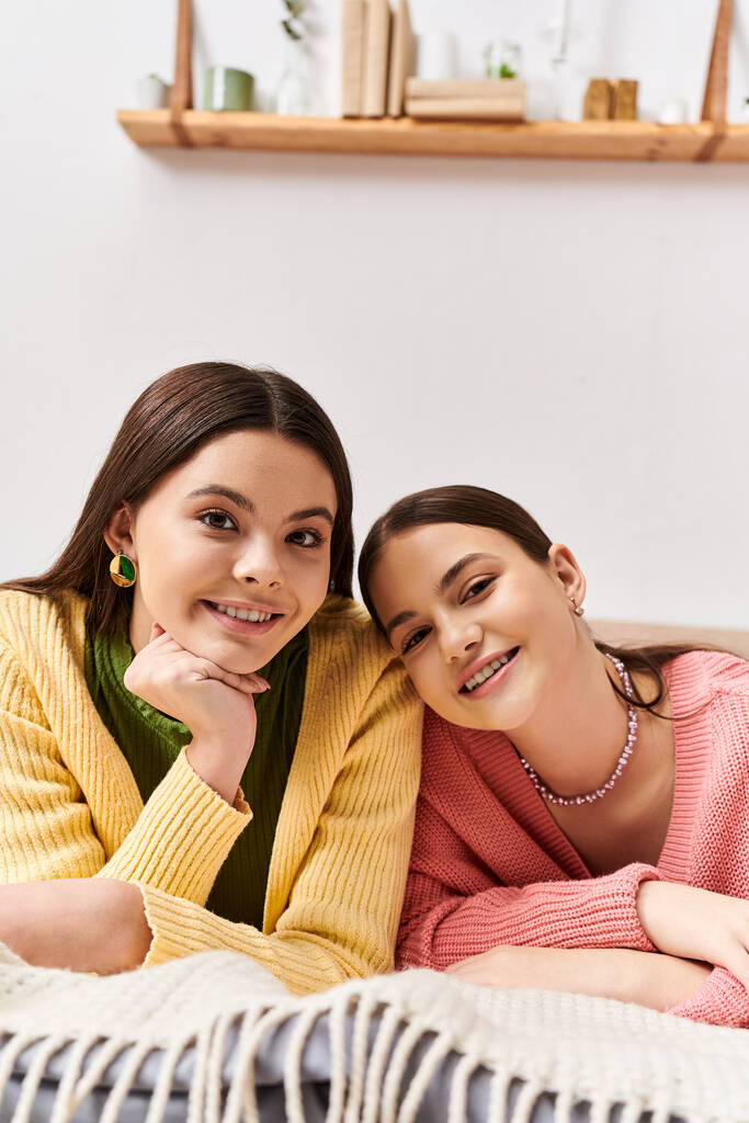 Zwei hübsche Mädchen im Teenageralter, lässig gekleidet, liegen nebeneinander auf einem Bett und genießen einen Moment friedlicher Zweisamkeit. - Foto, Bild