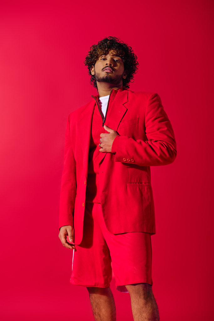 Stylish young Indian man in red suit strikes a pose against a vibrant backdrop. - Photo, Image