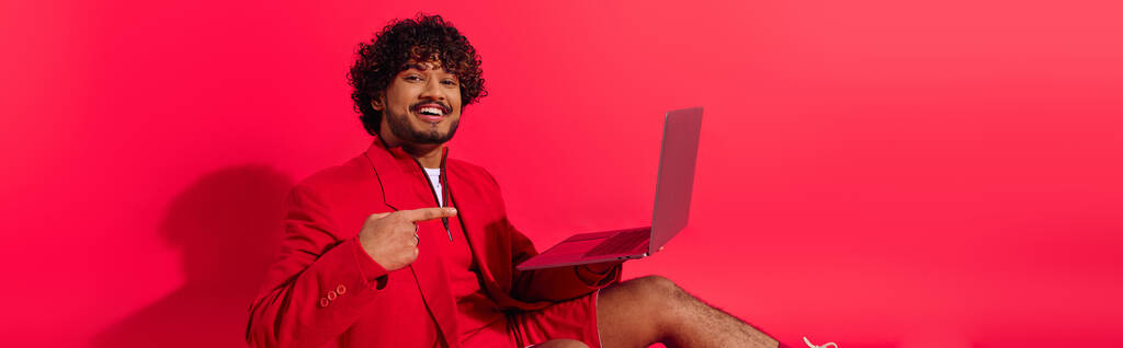Junger Inder in roter Jacke hält Laptop in der Hand. - Foto, Bild