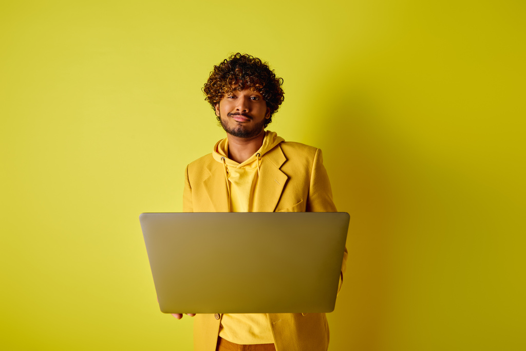 Красивый индиец в жёлтом костюме позирует с ноутбуком. - Фото, изображение