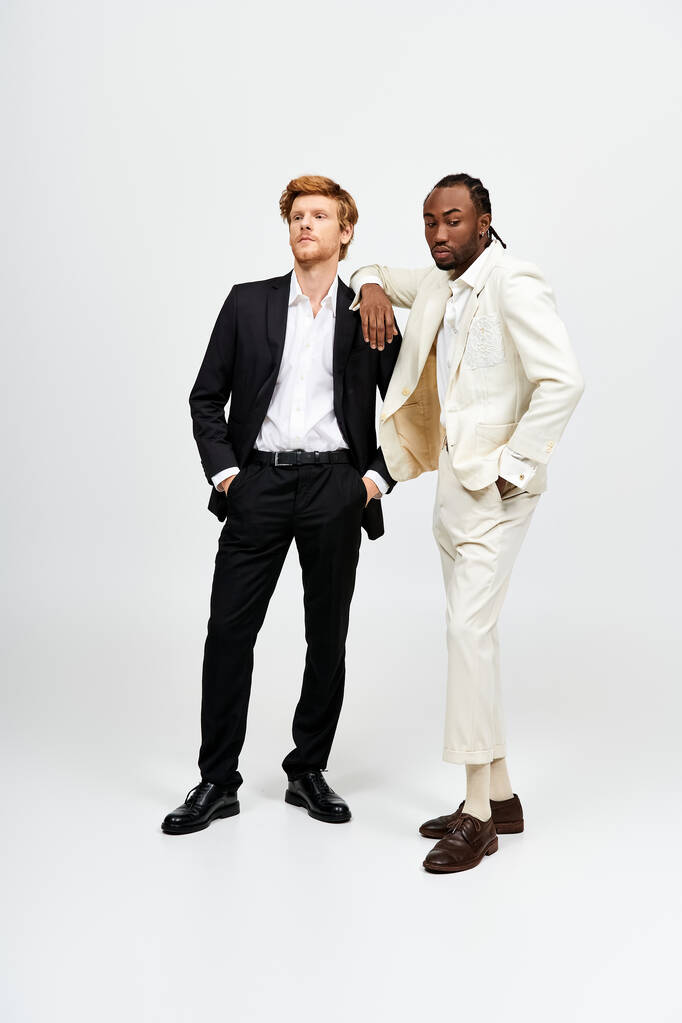 Dwóch przystojnych wielokulturowych mężczyzn w eleganckich garniturach stojących razem. - Zdjęcie, obraz