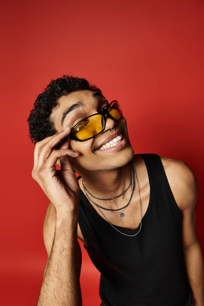 Όμορφος Αφροαμερικανός που φοράει γυαλιά ηλίου σε έντονο κόκκινο φόντο. - Φωτογραφία, εικόνα