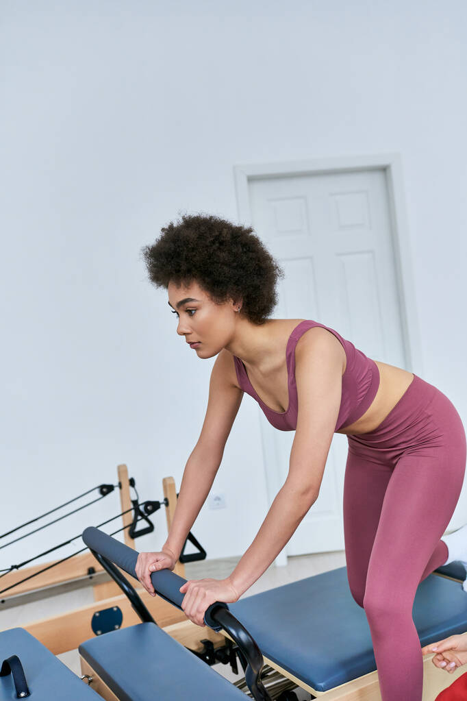 Eine Frau konzentriert sich in einem belebten Fitnessstudio auf ihr Rudergerät-Training. - Foto, Bild