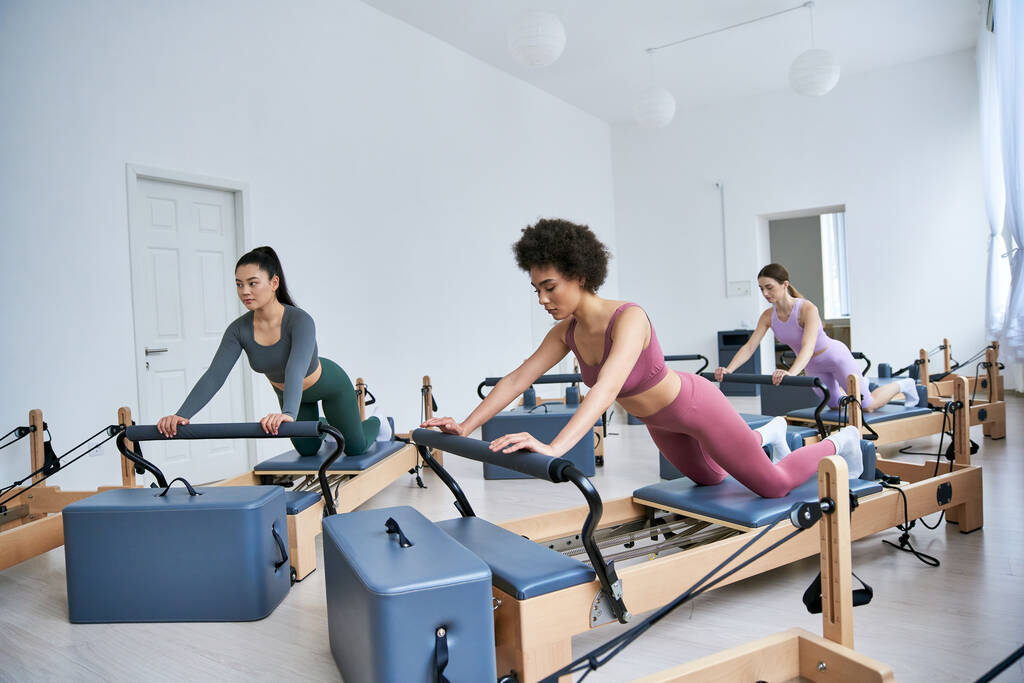 Groupe diversifié de femmes engagées dans une classe de pilates, concentrées et déterminées. - Photo, image