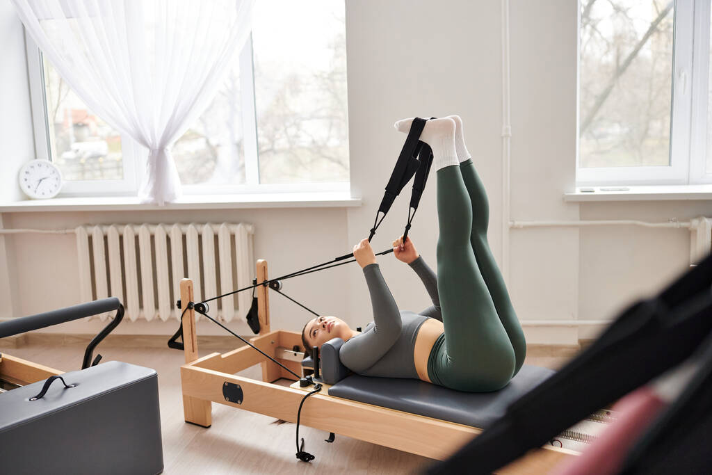 Femme attrayante effectue gracieusement des exercices lors d'une leçon de pilates. - Photo, image