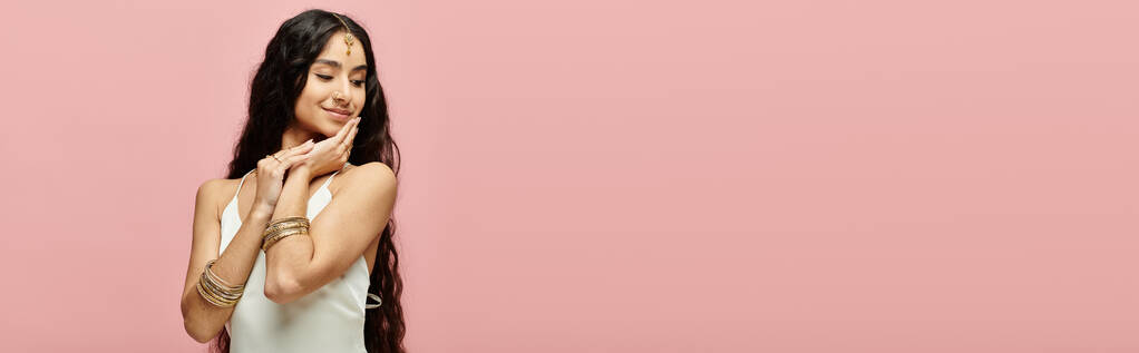 Fiatal indiai nő hosszú haj pózol egy rózsaszín háttér. - Fotó, kép