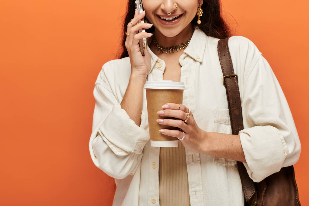 Una joven india chateando por teléfono mientras disfruta de una taza de café. - Foto, Imagen