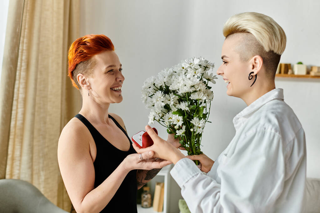 Dwie kobiety z krótkimi włosami wymieniają prezenty i uśmiecha się w przytulnym salonie, wyrażając radość i uczucie. - Zdjęcie, obraz