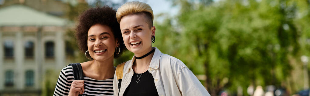 Дві молоді жінки, багатокультурна лесбійська пара, витончено ходять разом у парку біля університетського містечка. - Фото, зображення