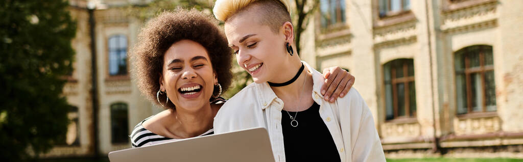 Deux femmes souriant joyeusement alors qu'elles collaborent sur un ordinateur portable ensemble. - Photo, image