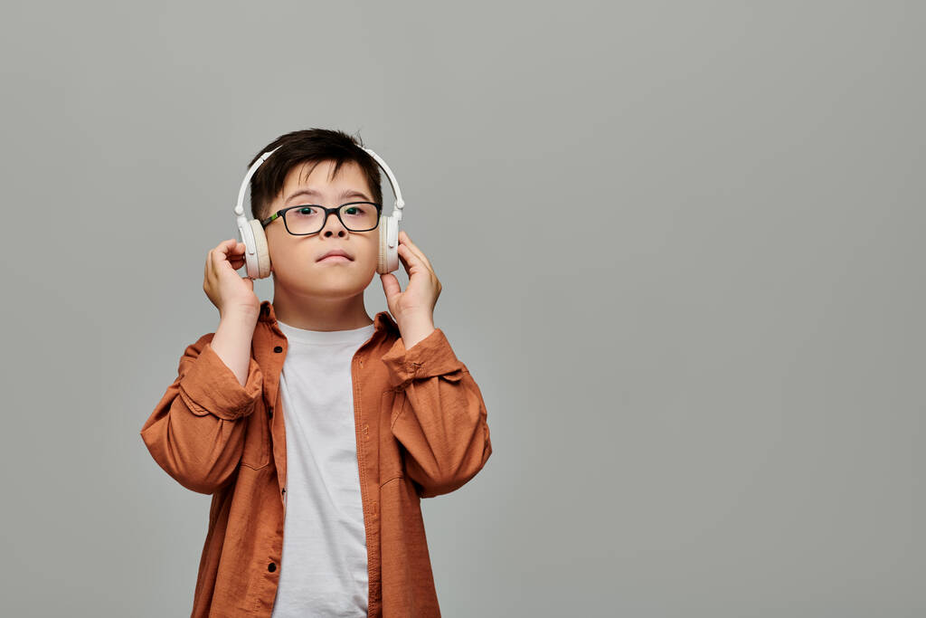Charming boy with Down syndrome felizmente escucha música en los auriculares. - Foto, imagen