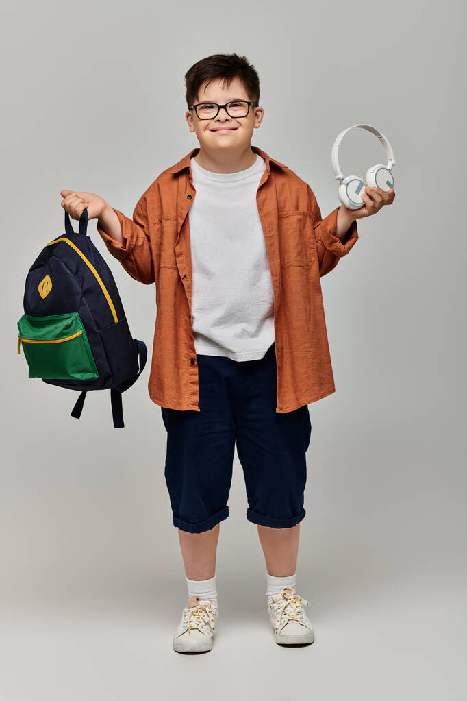 маленький хлопчик з синдромом Дауна з рюкзаком та навушниками. - Фото, зображення