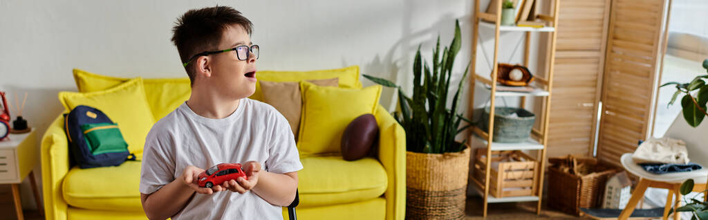 schattige jongen met Down syndroom ondergedompeld in een spel met speelgoed in gezellige woonkamer. - Foto, afbeelding
