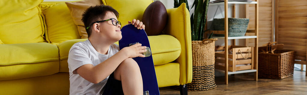 Cute boy with Down syndrome sitting on floor with vibrant yellow pillow - Photo, Image