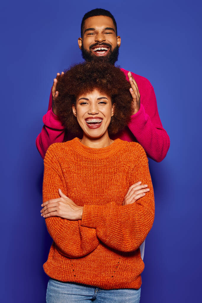 Um jovem afro-americano homem e mulher de pé lado a lado em trajes casuais vibrantes, mostrando seu forte vínculo de amizade. - Foto, Imagem