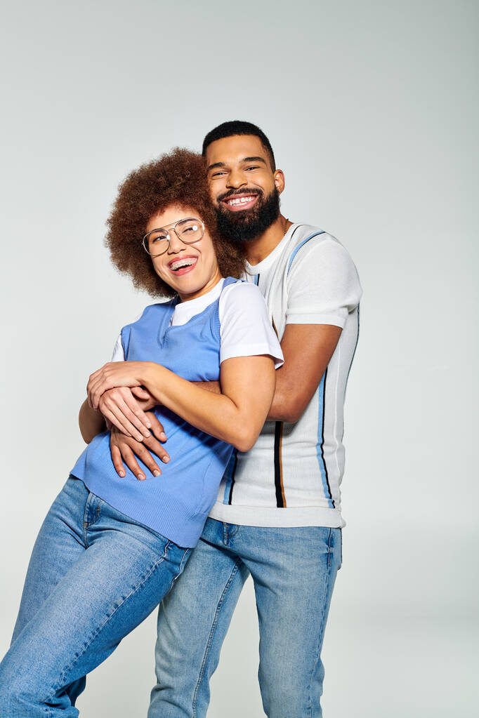 Stylově oblečený Afroameričan muž a žena pózují pro obrázek na šedém pozadí, ukazuje své přátelství. - Fotografie, Obrázek