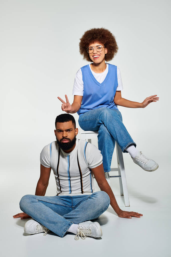 Een Afro-Amerikaanse man en vrouw in stijlvolle kleding zitten dicht, presentatie van vriendschap en kameraadschap. - Foto, afbeelding