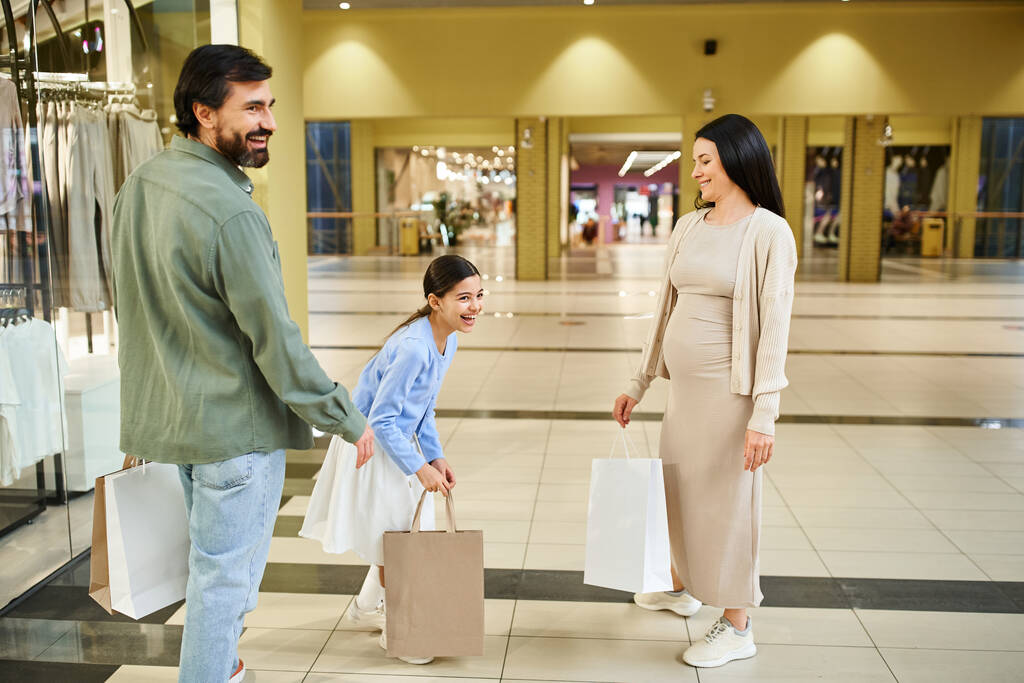 Szczęśliwy mężczyzna i kobieta przechadzają się po centrum handlowym, niosąc torby na zakupy wypełnione ostatnimi zakupami. - Zdjęcie, obraz