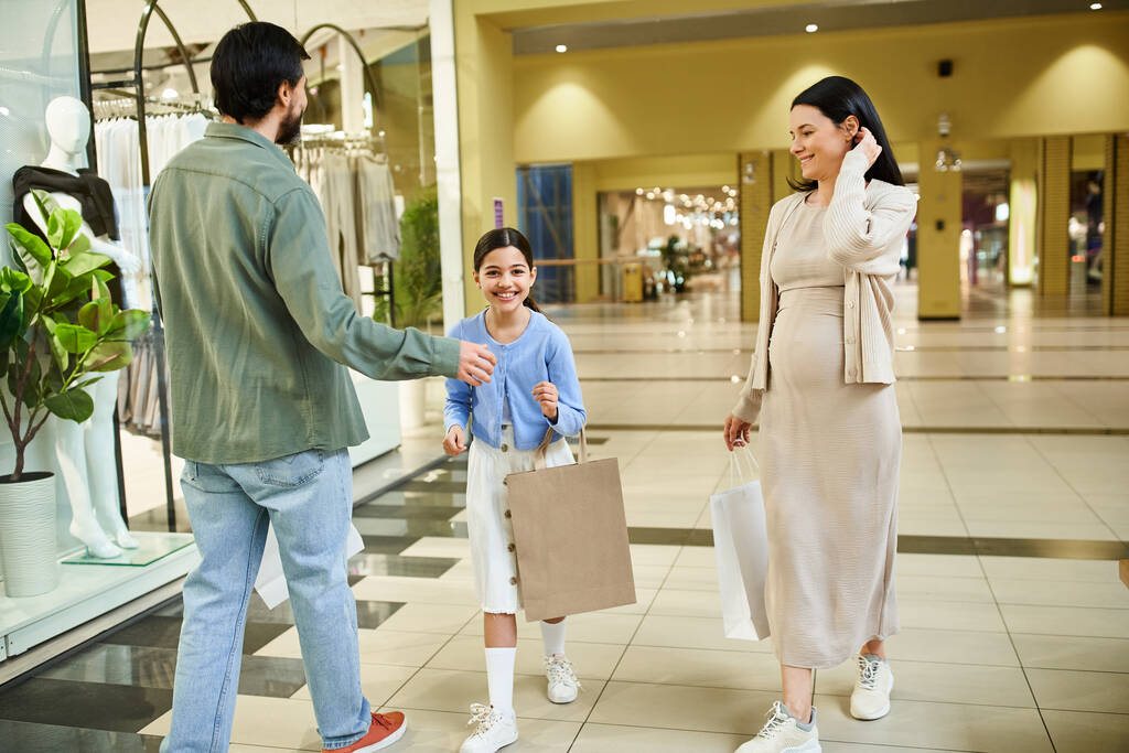 Muž a žena nakupují se svou dcerou, užívají si víkendový výlet v rušném obchoďáku plném obchodů a nakupujících. - Fotografie, Obrázek