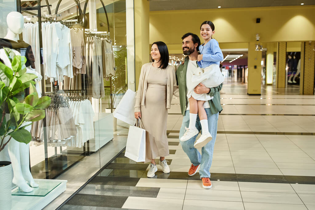 Una familia feliz, padres e hijos, paseando tranquilamente por un bullicioso centro comercial en una excursión de fin de semana. - Foto, imagen