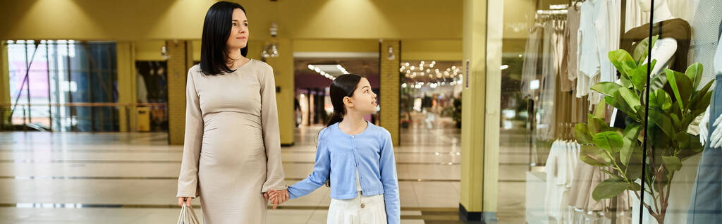 Una donna e un bambino camminano gioiosamente in un vivace centro commerciale, condividendo un momento di amicizia in mezzo alla frenesia dello shopping. - Foto, immagini