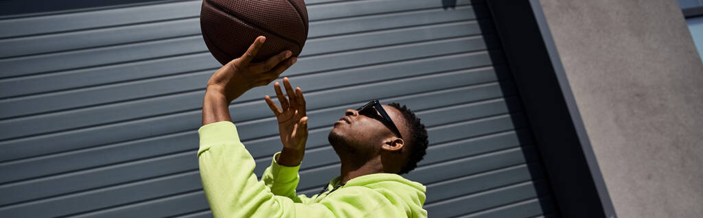 Ein eleganter junger afroamerikanischer Mann fängt elegant einen Basketball in der Luft. - Foto, Bild
