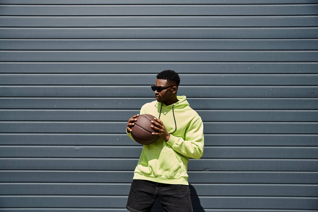 Young man in green hoodie holding basketball. - Photo, Image