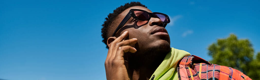 Beau Afro-Américain en lunettes de soleil posant activement. - Photo, image