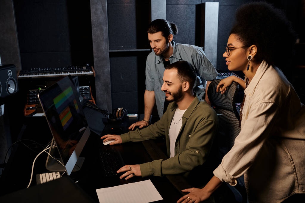 Un gruppo eterogeneo di musicisti che studia uno schermo di computer in uno studio di registrazione, focalizzato e impegnato nel processo creativo. - Foto, immagini