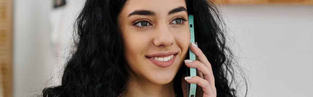 Молодая женщина с темными волосами разговаривает по мобильному телефону. - Фото, изображение
