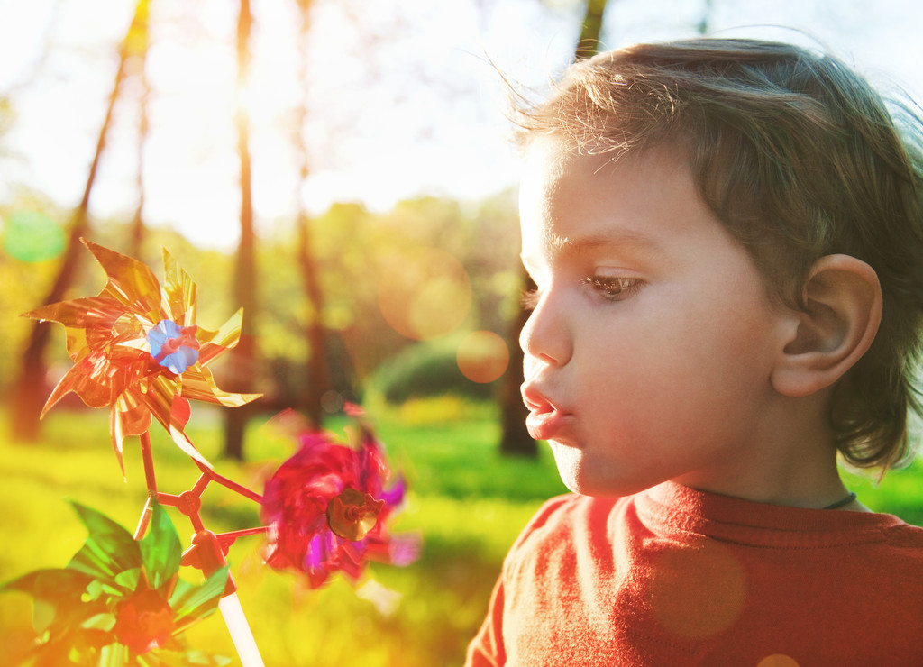 Retrato de um menino bonito soprando roda de vento em sol
 - Foto, Imagem