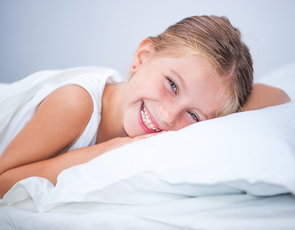 Piccola ragazza sorridente a letto
 - Foto, immagini