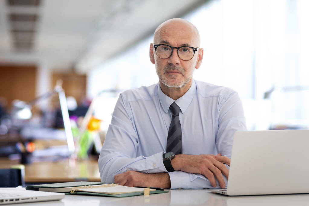 A middle-aged businessman sitting in the office. The man has a serious face and is wearing a shirt. - Photo, Image