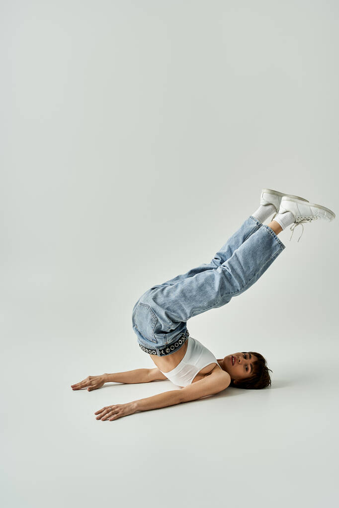 Stylish young woman doing a handstand on white background. - Фото, зображення