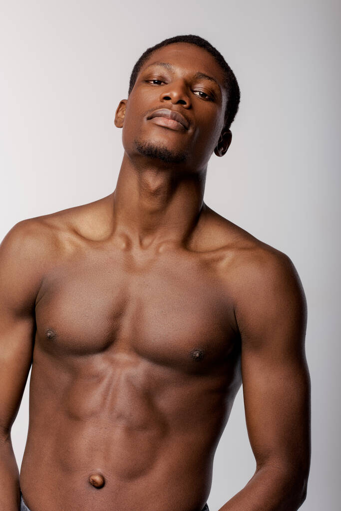 Ένας Αφροαμερικάνος στέκεται γυμνός μπροστά σε λευκό τοίχο.. - Φωτογραφία, εικόνα