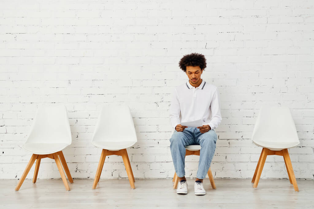 L'uomo circondato da sedie bianche in una mostra artistica di solitudine. - Foto, immagini