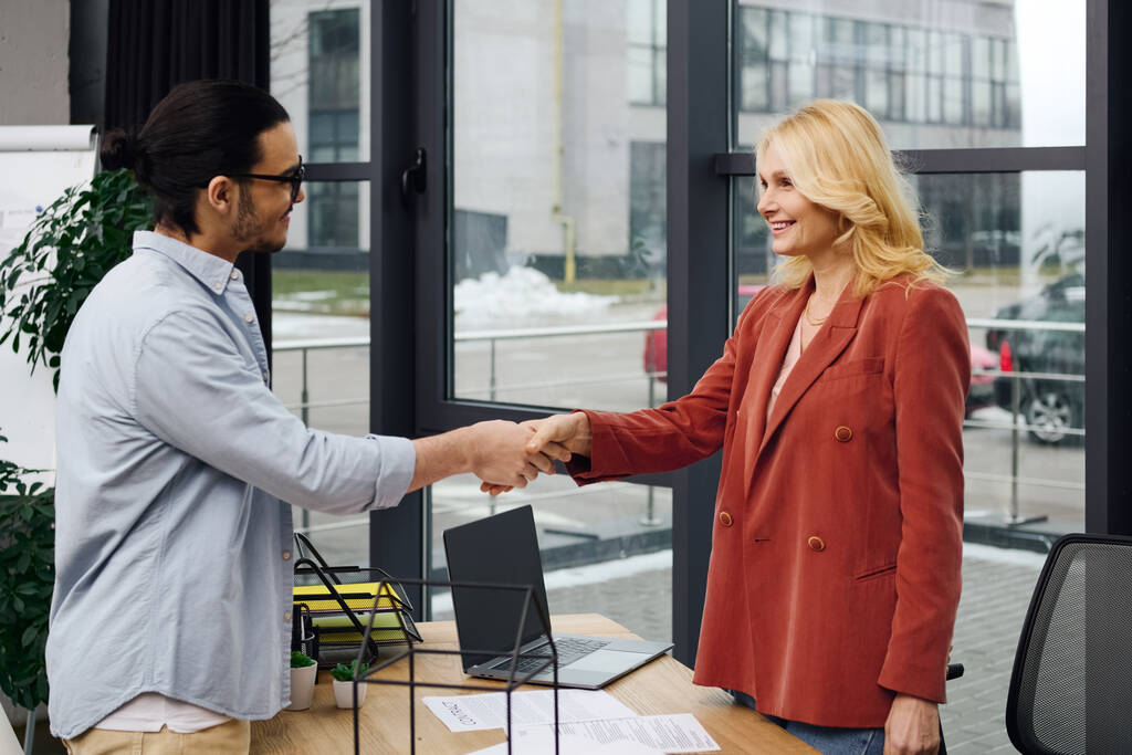 Um homem e uma mulher em um escritório apertando as mãos durante uma entrevista de emprego. - Foto, Imagem