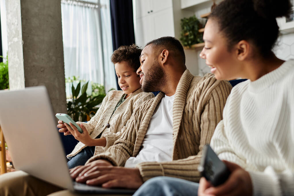 African american family engaged with laptop on couch. - Photo, Image
