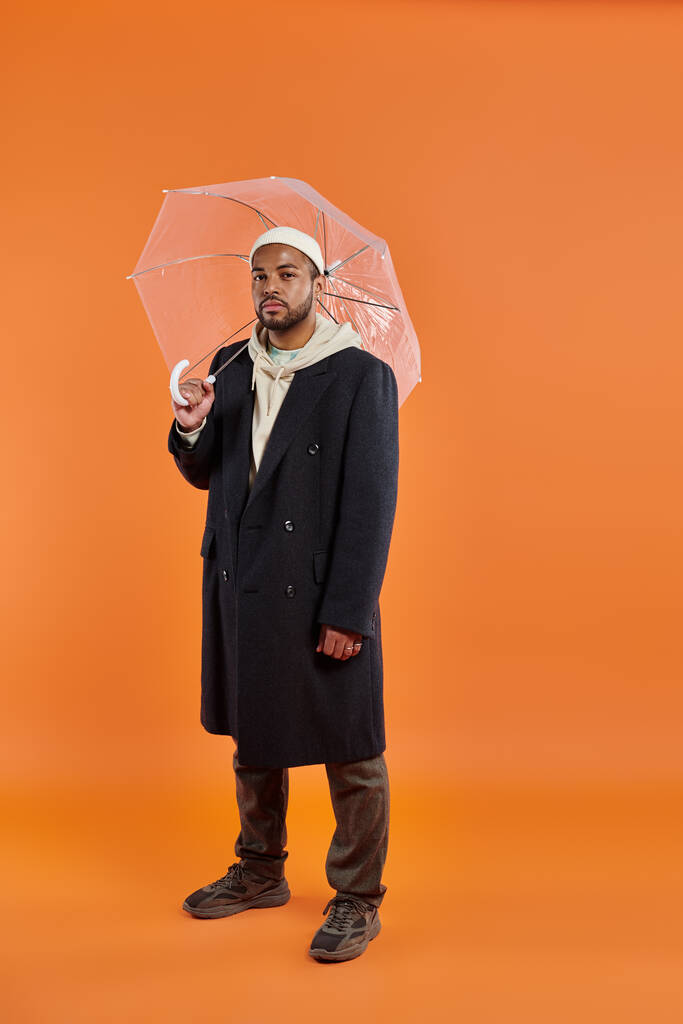 Africano americano homem elegantemente segurando guarda-chuva contra o pano de fundo vibrante. - Foto, Imagem