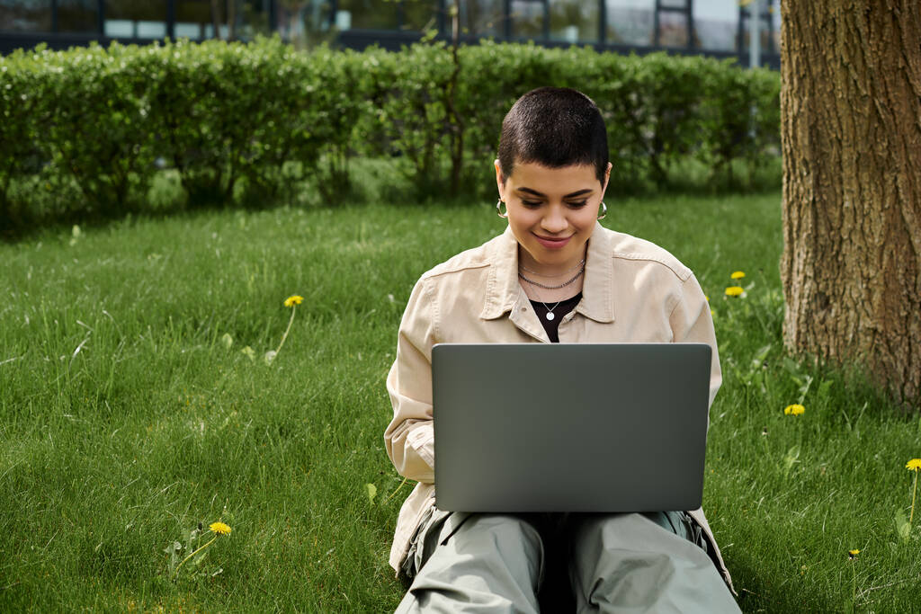 gen z chica con pelo corto con ordenador portátil en la hierba. - Foto, imagen