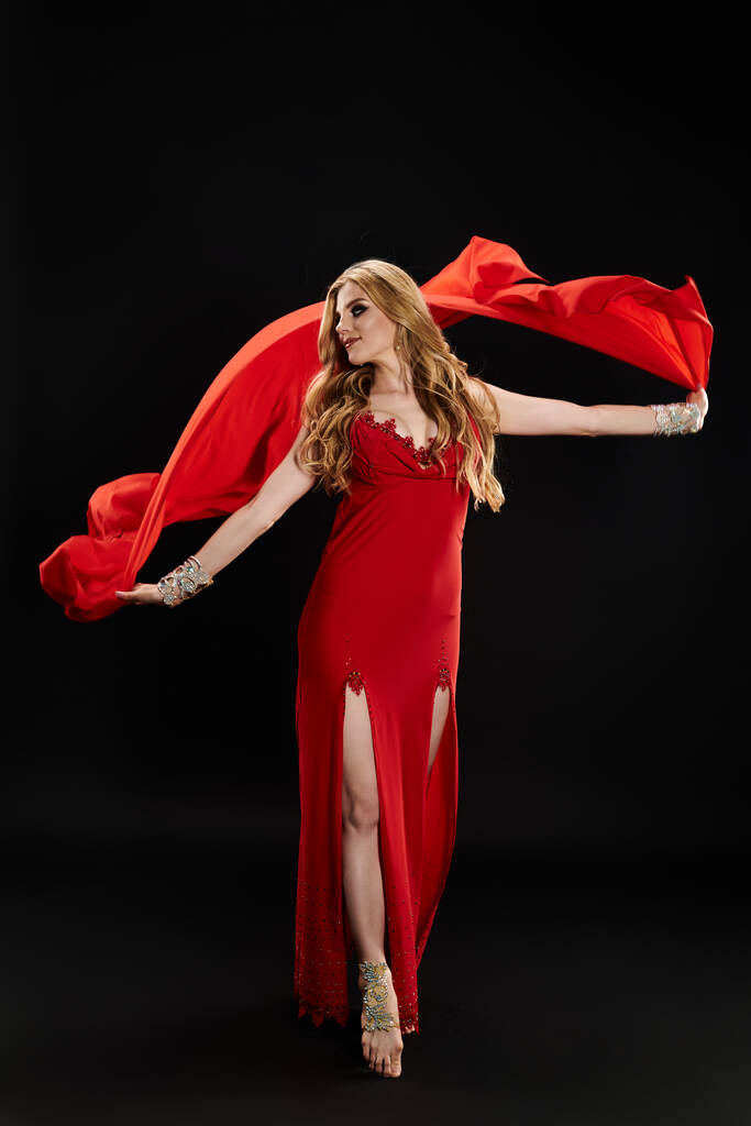 Hermosa mujer en vestido rojo con gracia baila con bufanda roja. - Foto, Imagen