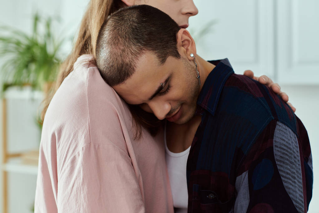 Um casal gay em roupas casuais compartilhando um abraço caloroso, expressando amor e intimidade em um ambiente acolhedor em casa. - Foto, Imagem