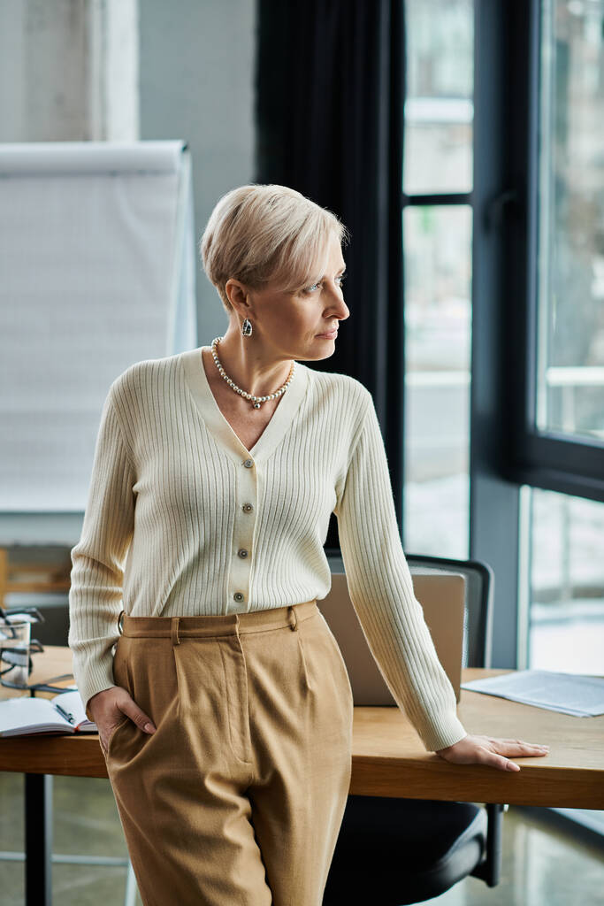 Geschäftsfrau mittleren Alters in modernem Büro an einem polierten Holztisch. - Foto, Bild