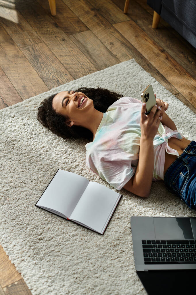 ノートパソコンを使って床に横たわる女性. - 写真・画像
