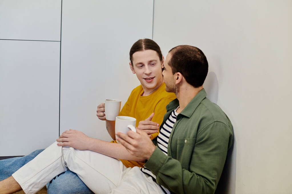 Mladý homosexuální pár relaxuje a vychutnává kávu společně v moderním bytě. - Fotografie, Obrázek